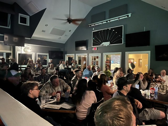 Teams gathered around tables during a busy game night